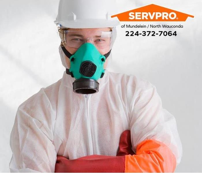 A mold remediation technician wears a hazmat suit and respirator.