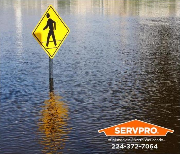 A crosswalk sign is underwater from flooding.