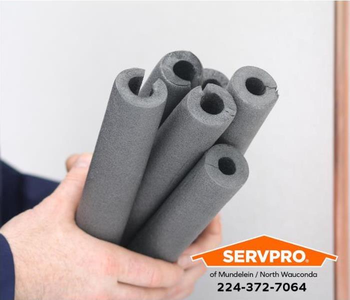 A person holds pipe insulation sleeves. 