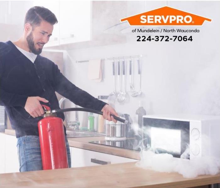 A person uses a fire extinguisher to put out a microwave fire.